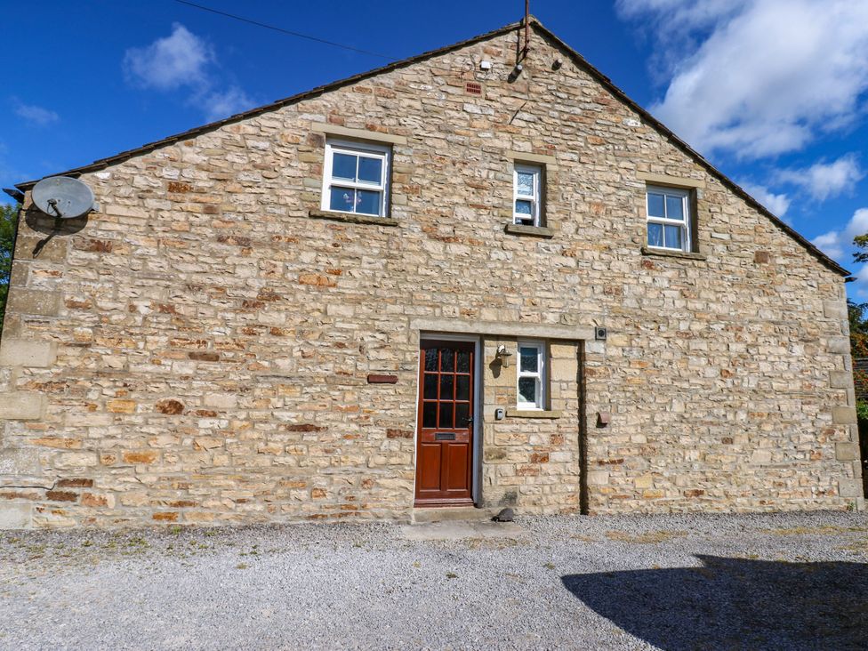 A stone house with a wooden door and windows at Barnbrook in Carperby near Leyburn