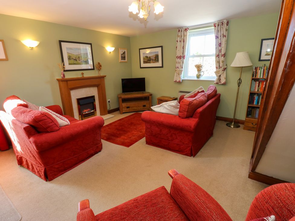 A living room with red sofas and a television at Barnbrook Carperby near Leyburn