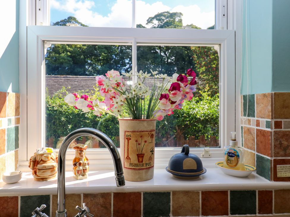 A kitchen window with faux flowers and various items on the sill at Barnbrook in Carperby near Leyburn