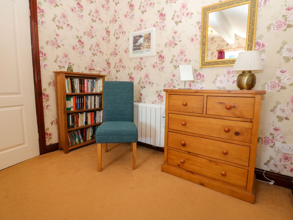 A bedroom with a chair and bookshelf at Barnbrook in Carperby near Leyburn
