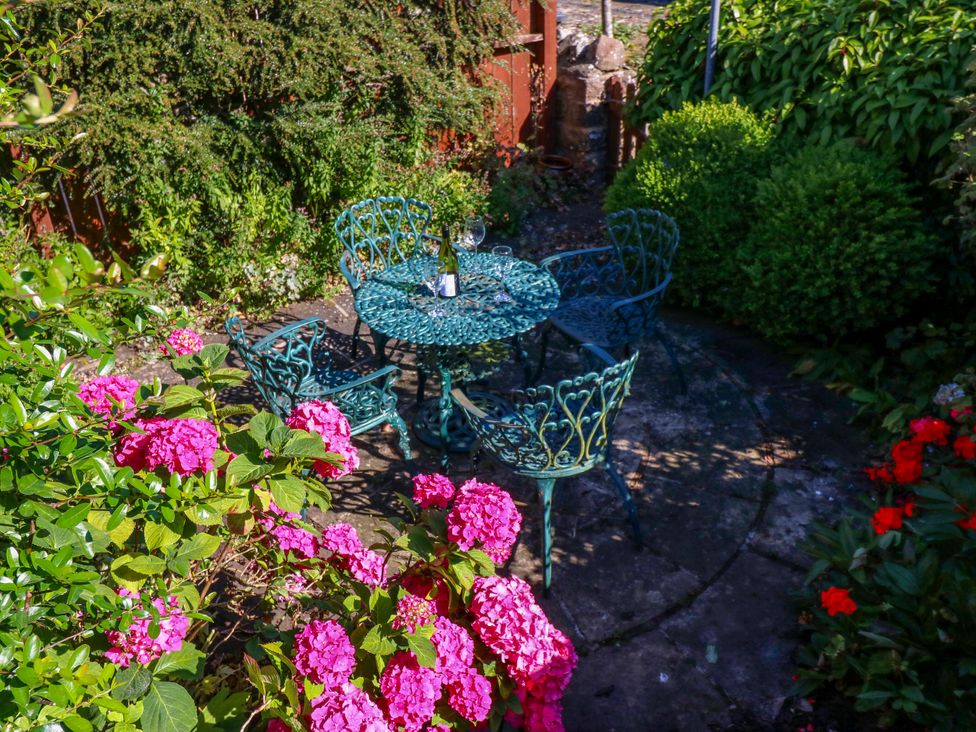 A garden with a table and chairs among flowers at Barnbrook in Carperby near Leyburn