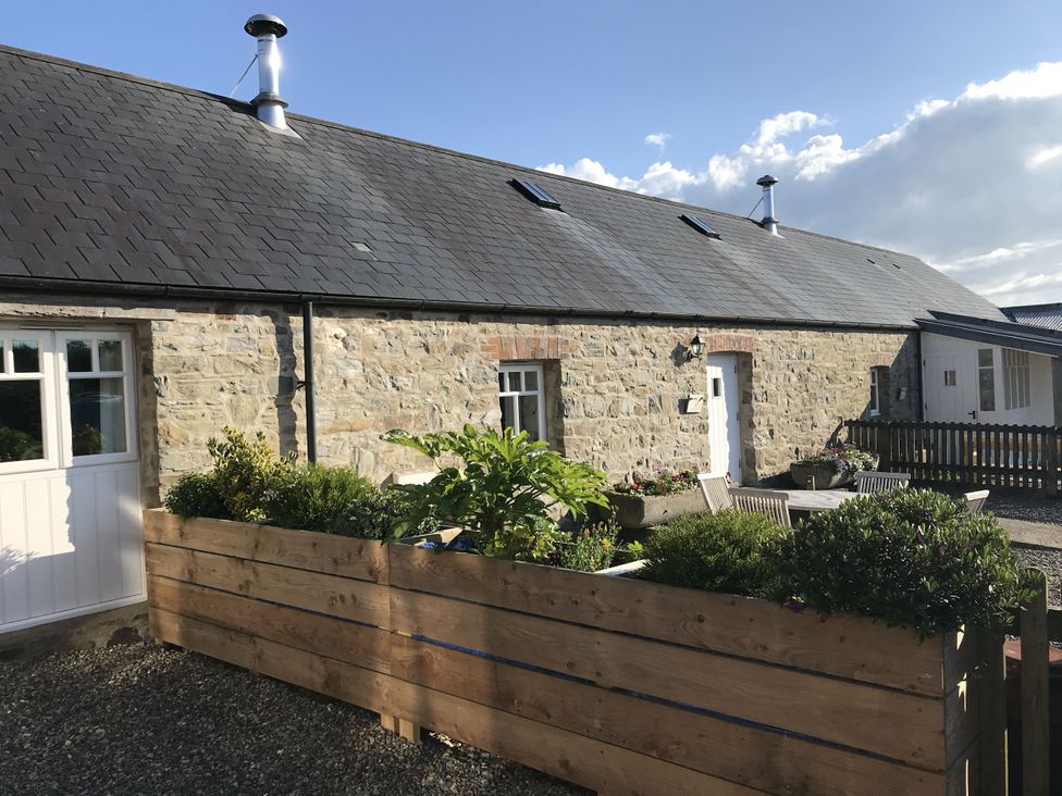 An outdoor view of a stone building with plants and a gravel area at Bwthyn Bach in Newport