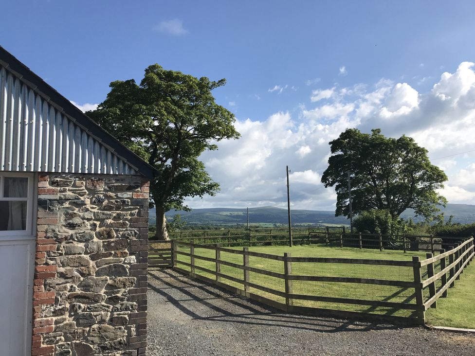 A fenced area with trees and a stone wall at Y Cartws in Newport