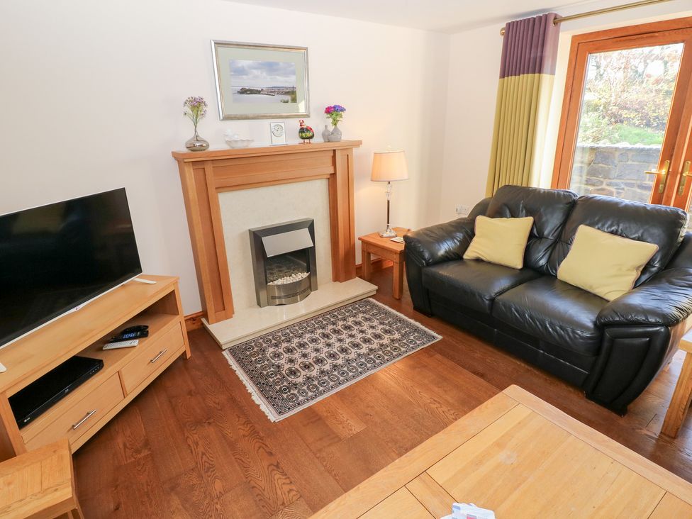 A living room with a sofa and television at Bwthyn Trecoed in St. Clears near Carmarthen