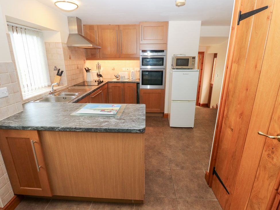 A kitchen with cabinets, a sink, and appliances at Bwthyn Trecoed in St. Clears near Carmarthen
