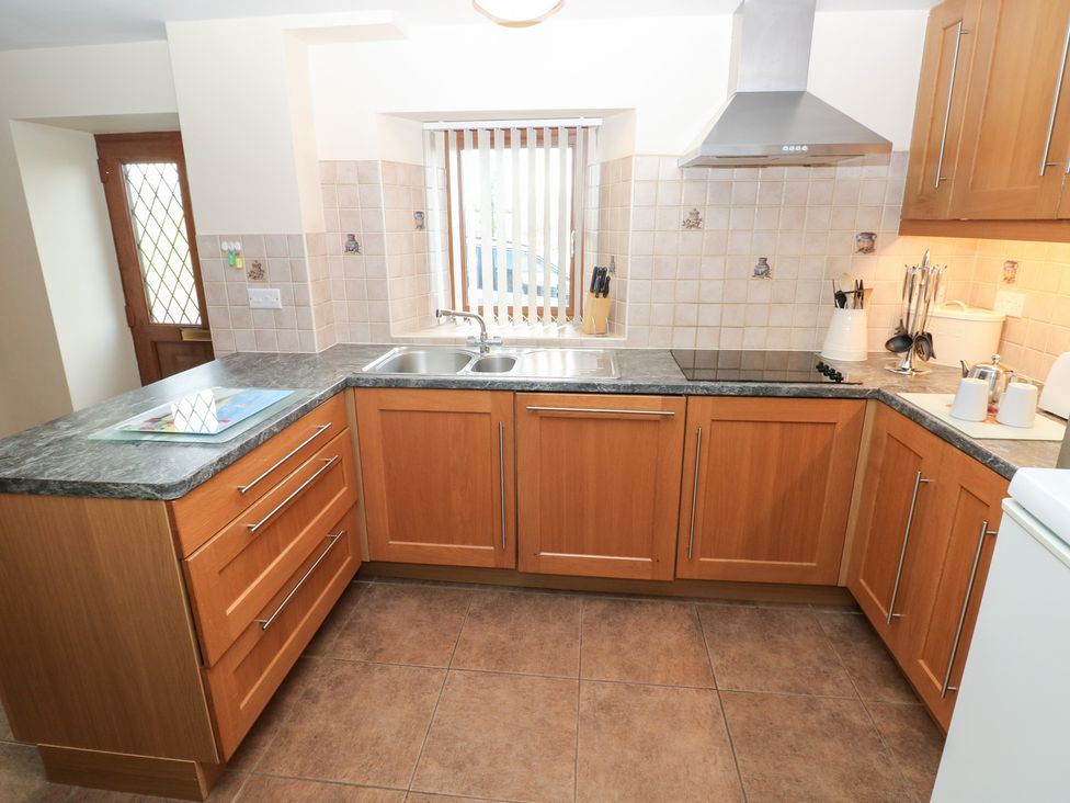 A kitchen with wooden cabinets and a sink at Bwthyn Trecoed St. Clears near Carmarthen