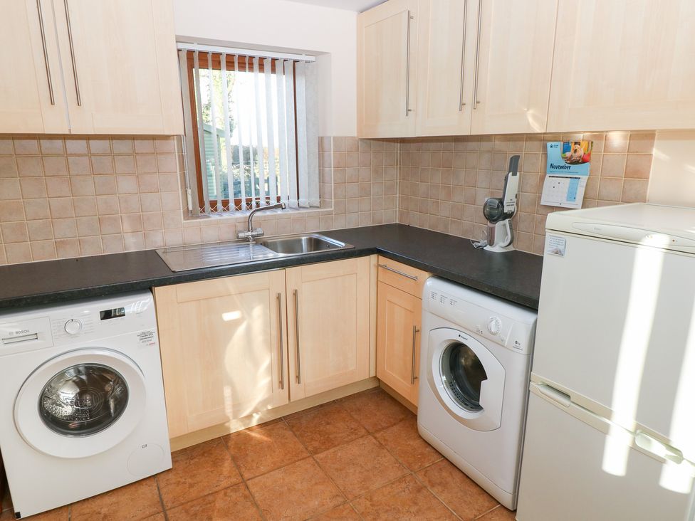 A kitchen with a washing machine and refrigerator at Bwthyn Trecoed in St. Clears near Carmarthen
