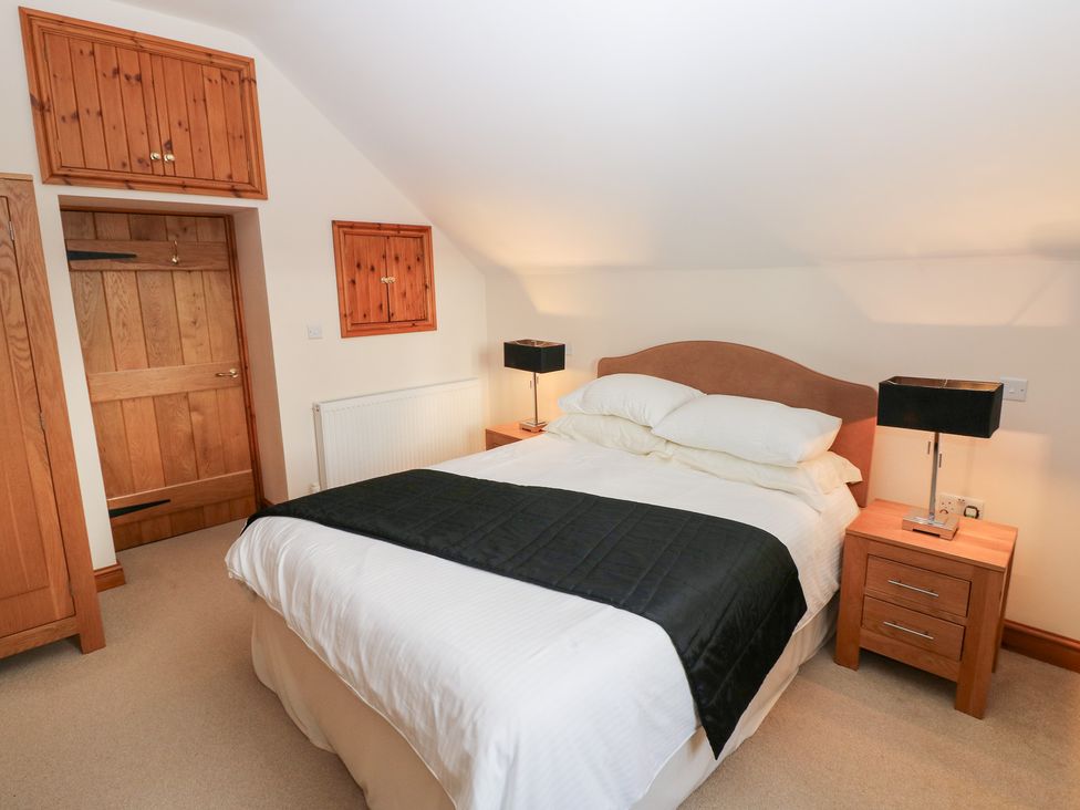 A bedroom with a bed and nightstands at Bwthyn Trecoed St. Clears near Carmarthen
