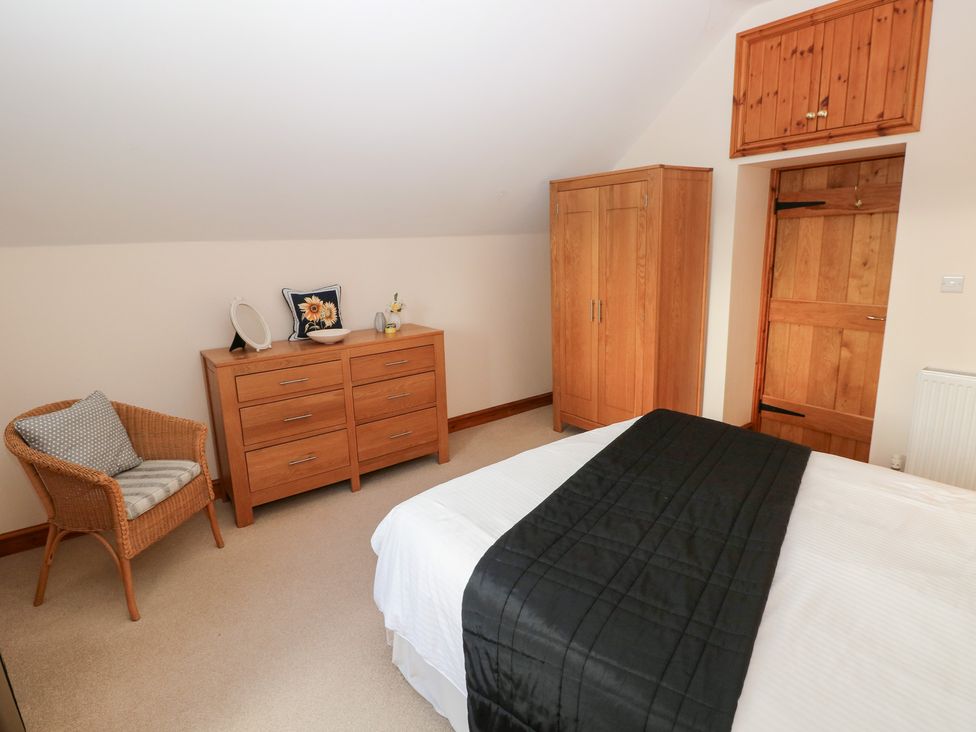 A bedroom with furniture including a bed, dresser, and wardrobe at Bwthyn Trecoed St. Clears near Carmarthen