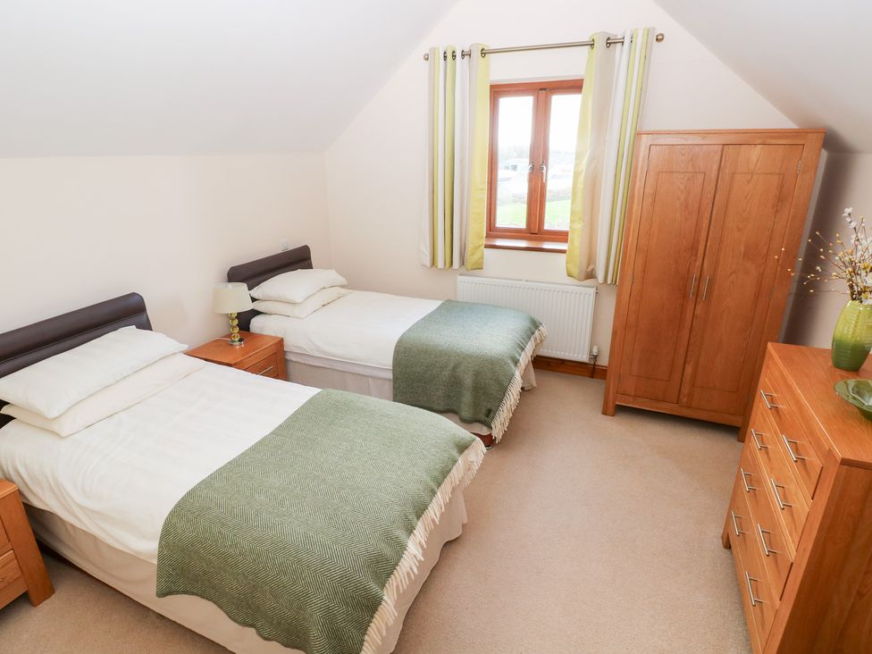 A bedroom with two single beds and wooden furniture at Bwthyn Trecoed St. Clears near Carmarthen