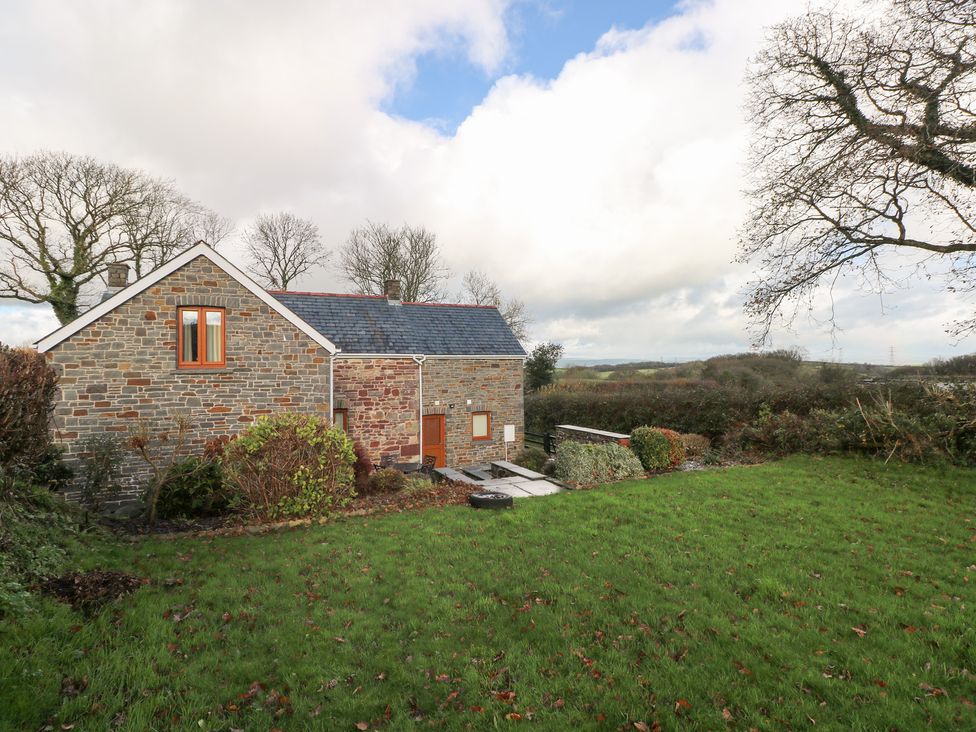 A stone house with green grass and trees at Bwthyn Trecoed St. Clears near Carmarthen