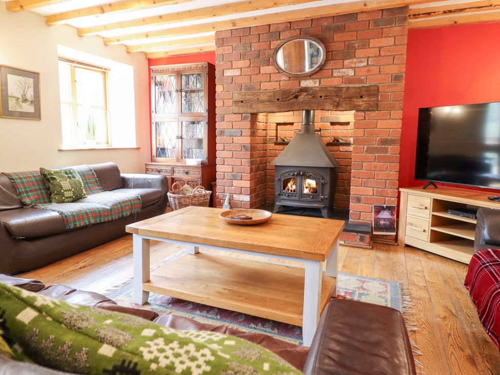 A living room with a sofa, table, and fireplace at Ysgubor Pwlliago, Pennant Valley near Llangynog