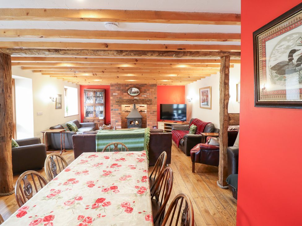 A living room with a dining area and a fireplace at Ysgubor Pwlliago near Pennant Valley near Llangynog