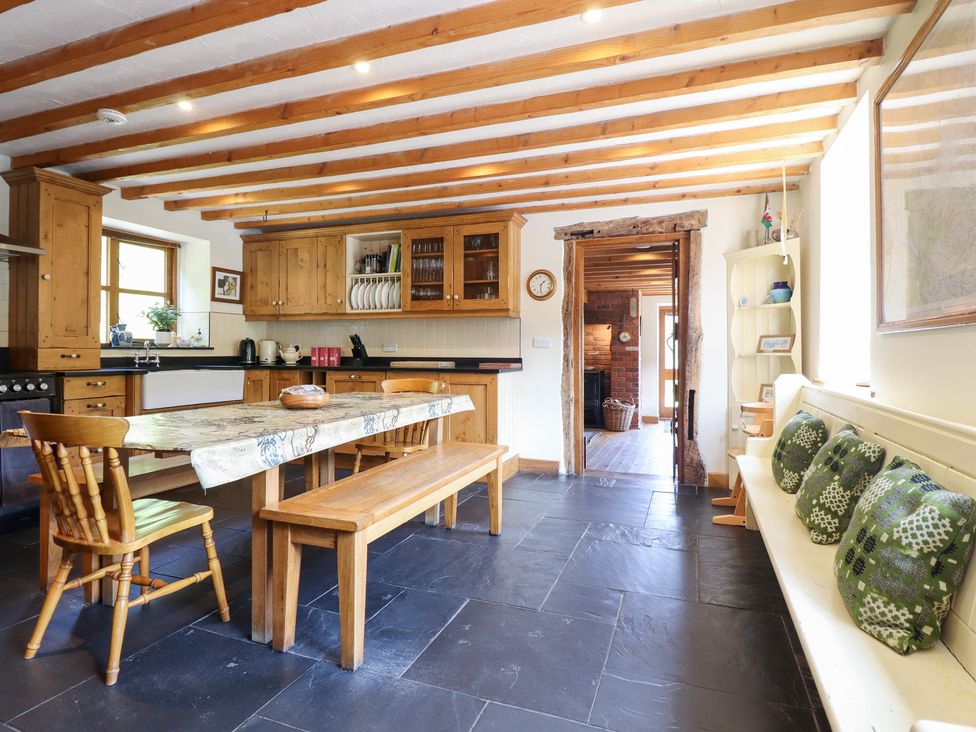 A kitchen with wooden cabinets and a dining table at Ysgubor Pwlliago in Pennant Valley near Llangynog
