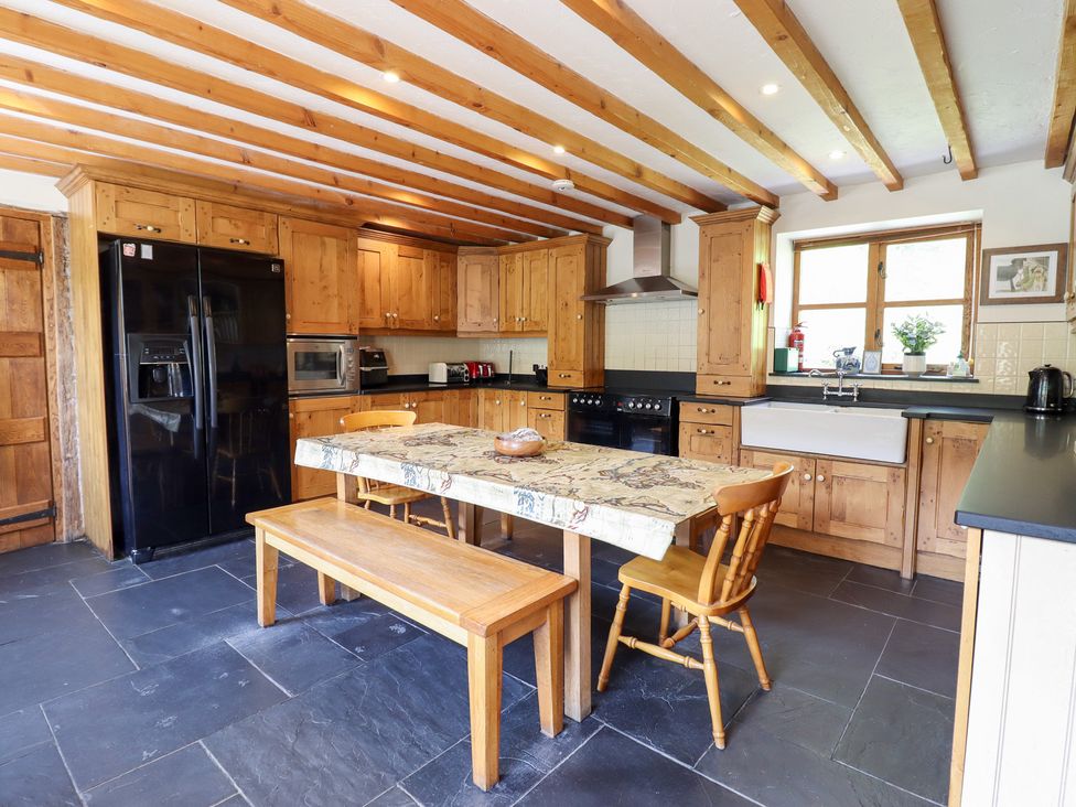 A kitchen with wooden cabinets and black appliances at Ysgubor Pwlliago in Pennant Valley near Llangynog