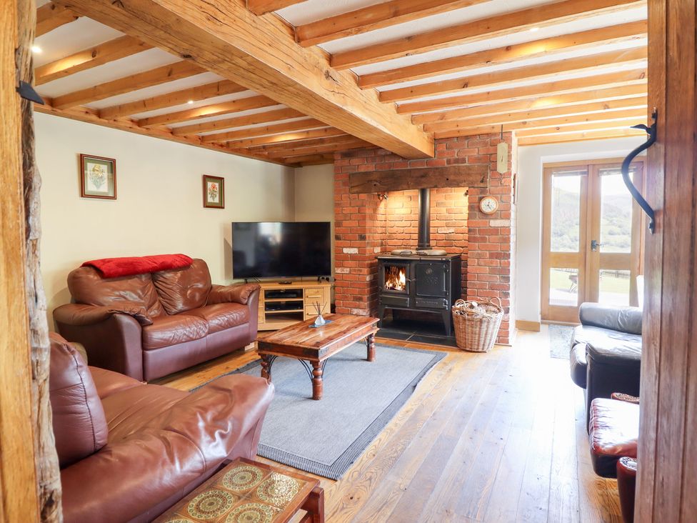 A living room with a wood stove and television at Ysgubor Pwlliago, Pennant Valley near Llangynog