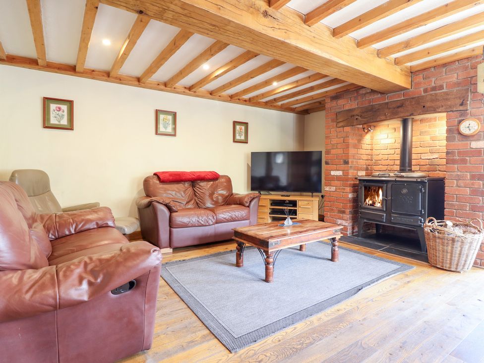 A living room with a sofa and a wood stove at Ysgubor Pwlliago Pennant Valley near Llangynog