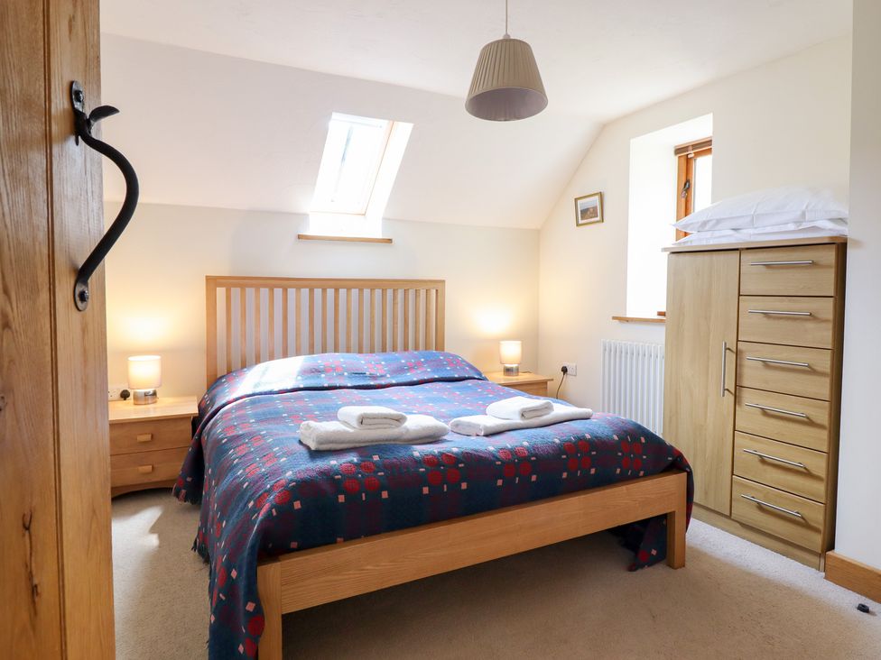 A bedroom with a bed and wardrobe at Ysgubor Pwlliago Pennant Valley near Llangynog