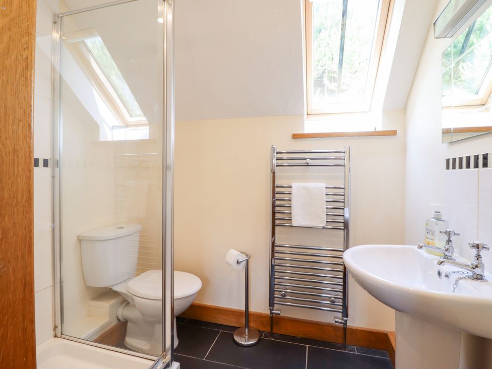A bathroom featuring a shower, toilet, and sink at Ysgubor Pwlliago in Pennant Valley near Llangynog