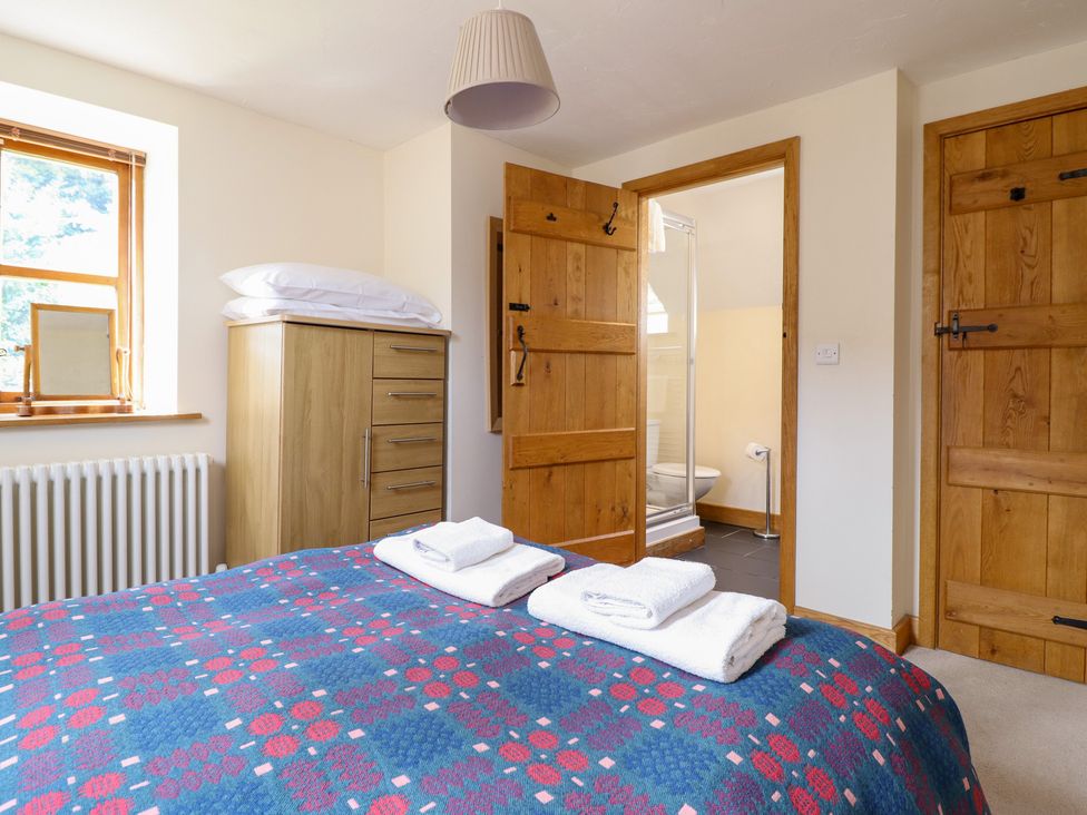 A bedroom with a bed and wardrobe at Ysgubor Pwlliago in Pennant Valley near Llangynog