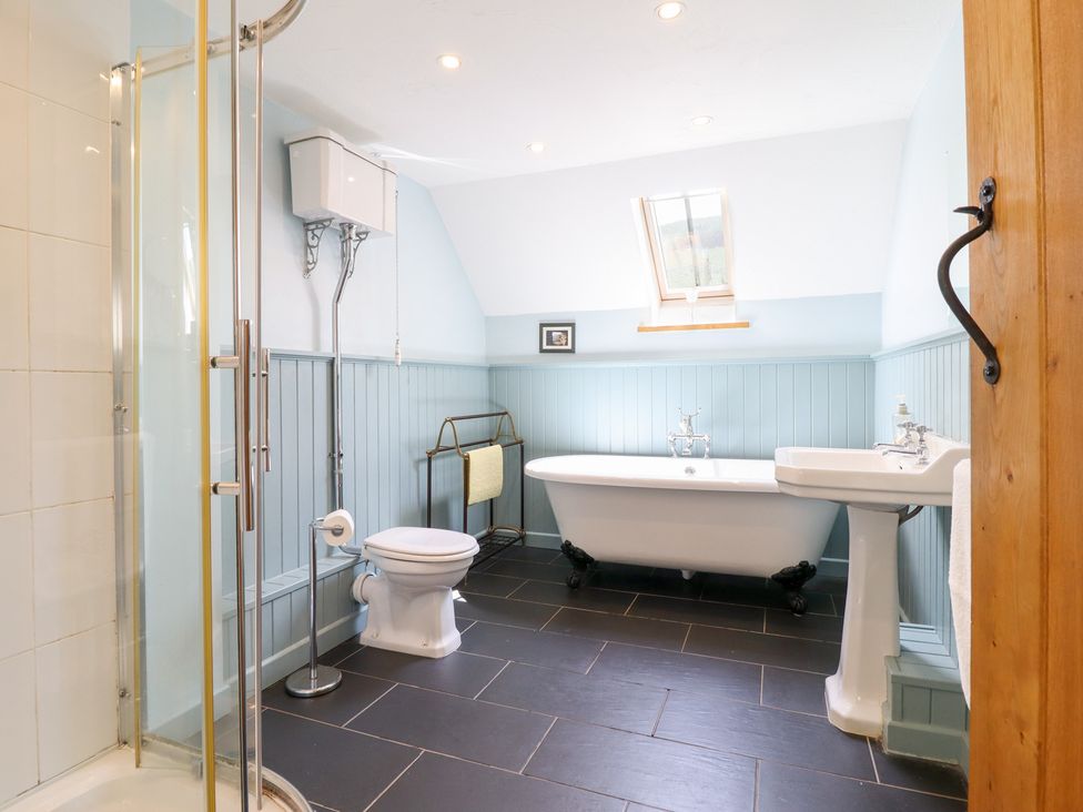 A bathroom with a bathtub, toilet, shower, and sink at Ysgubor Pwlliago in Pennant Valley near Llangynog