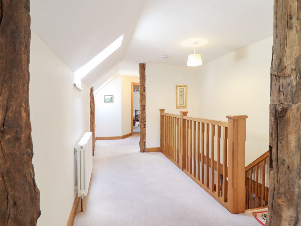 A hallway with wooden railing and staircase at Ysgubor Pwlliago Pennant Valley near Llangynog