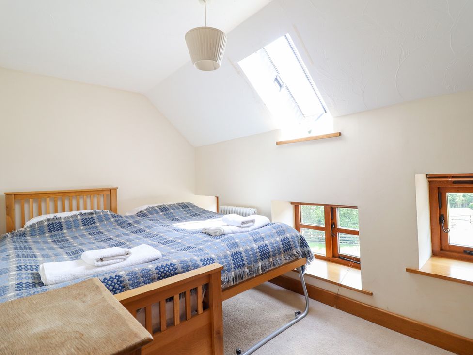 A bedroom with a bed and windows at Ysgubor Pwlliago in Pennant Valley near Llangynog