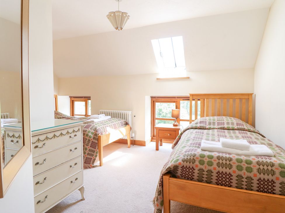 A bedroom with two single beds and a mirror at Ysgubor Pwlliago in Pennant Valley near Llangynog