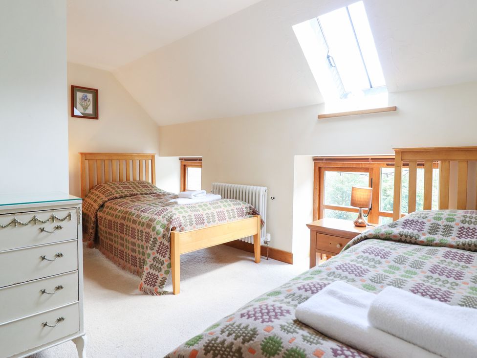 A bedroom with two beds and a bedside table at Ysgubor Pwlliago, Pennant Valley near Llangynog