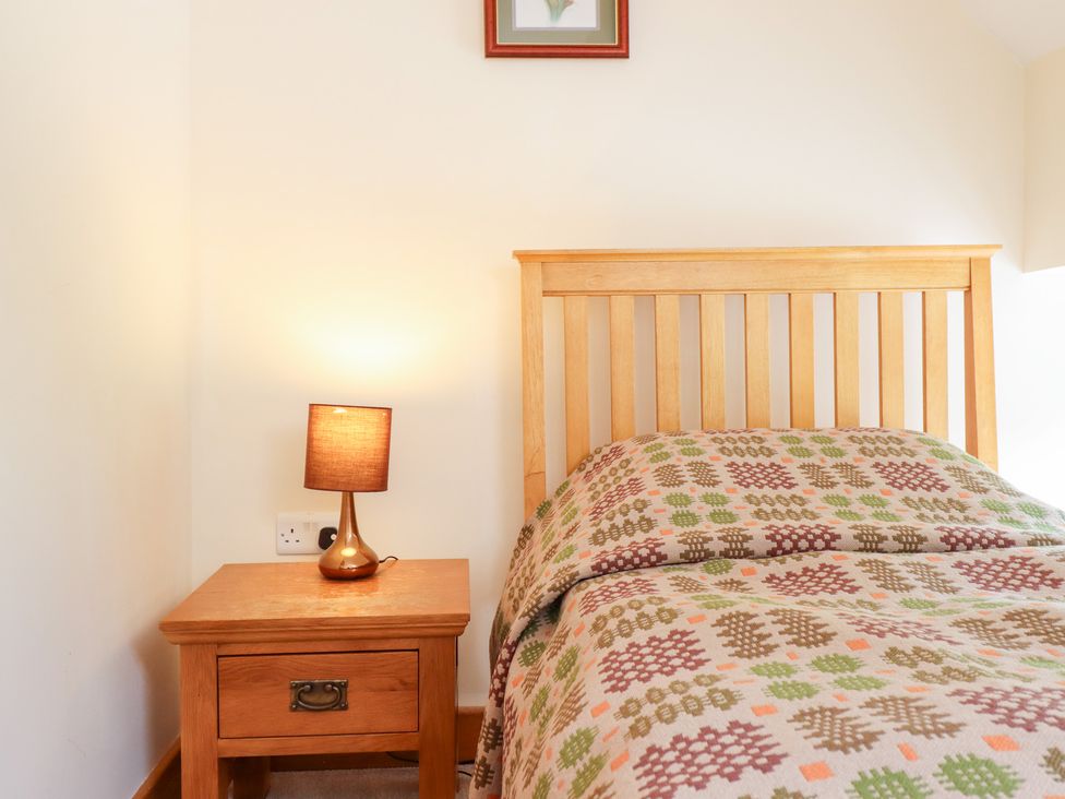 A bedroom with a bed and lamp at Ysgubor Pwlliago in Pennant Valley near Llangynog