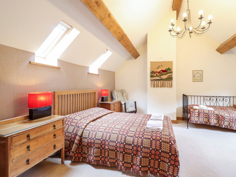 A bedroom with two beds and nightstands at Ysgubor Pwlliago, Pennant Valley near Llangynog