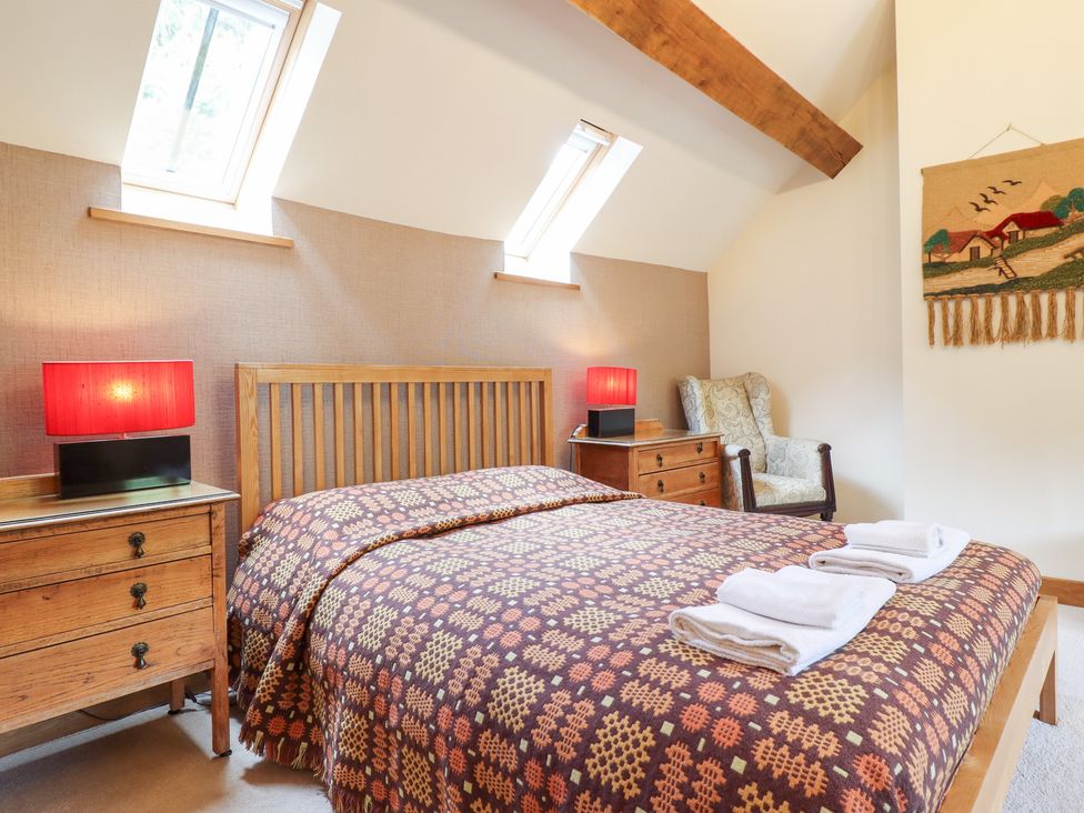 A bedroom with a bed and bedside tables at Ysgubor Pwlliago, Pennant Valley near Llangynog