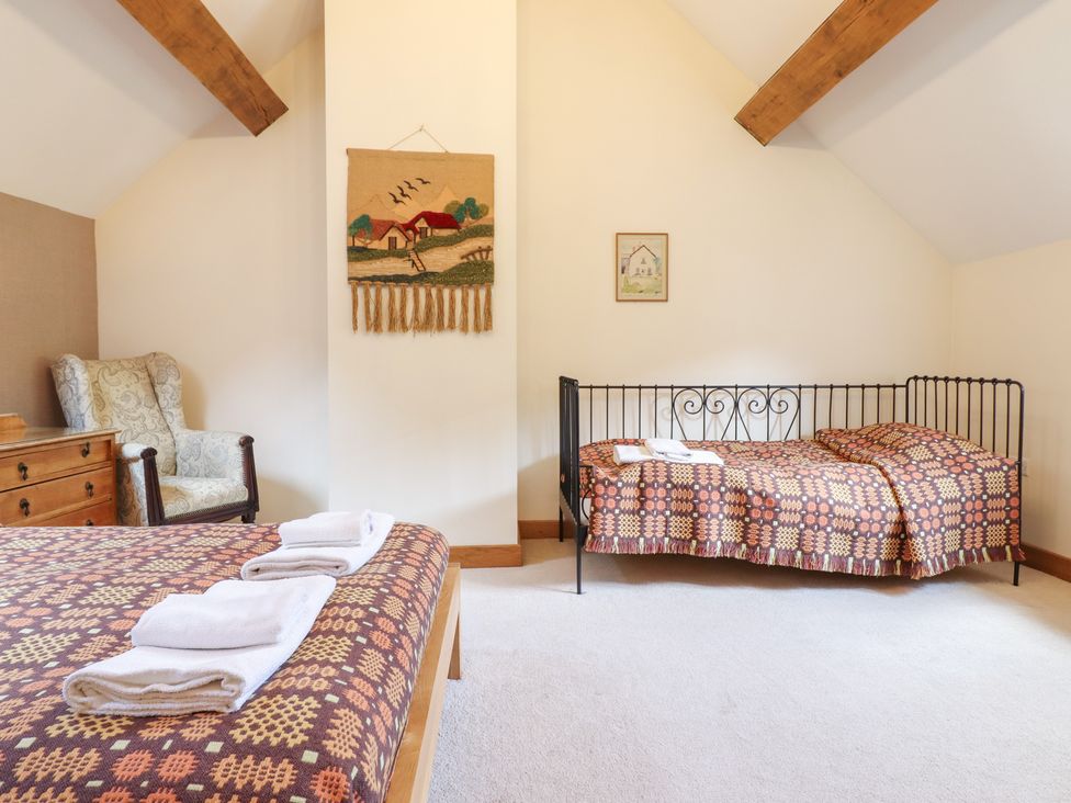 A bedroom with a bed and an armchair at Ysgubor Pwlliago Pennant Valley near Llangynog