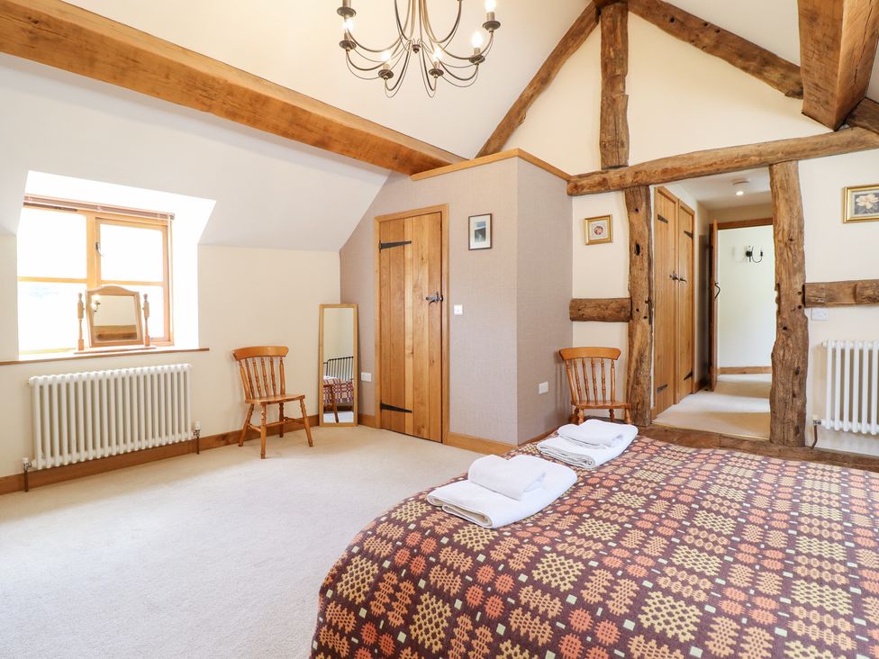 A bedroom with a bed, chairs, and a mirror at Ysgubor Pwlliago in Pennant Valley near Llangynog