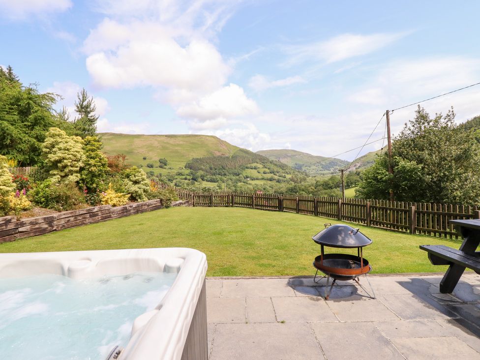 A garden with a hot tub and fire pit at Ysgubor Pwlliago, Pennant Valley near Llangynog