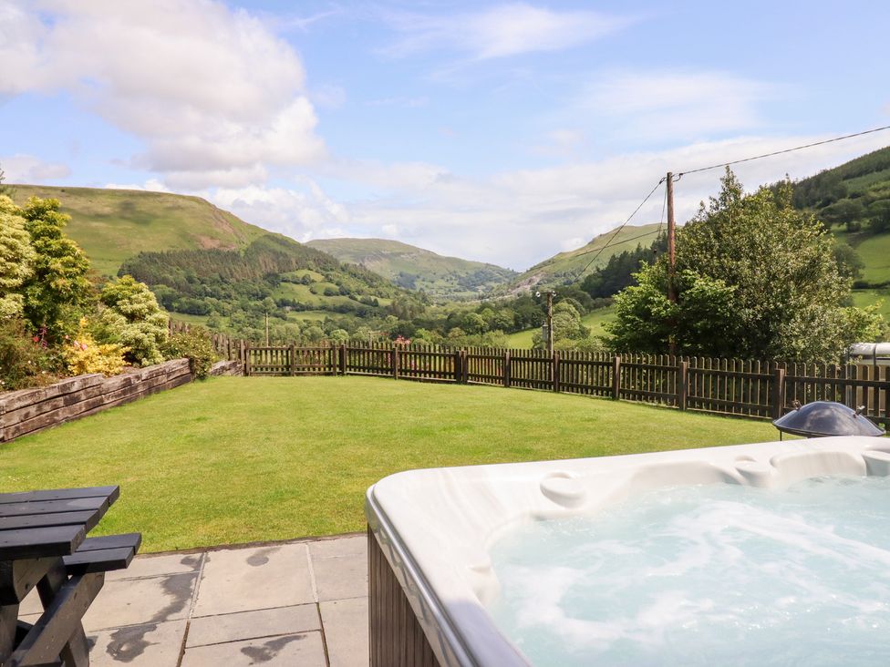 A garden with a hot tub and mountains in the background at Ysgubor Pwlliago Pennant Valley near Llangynog