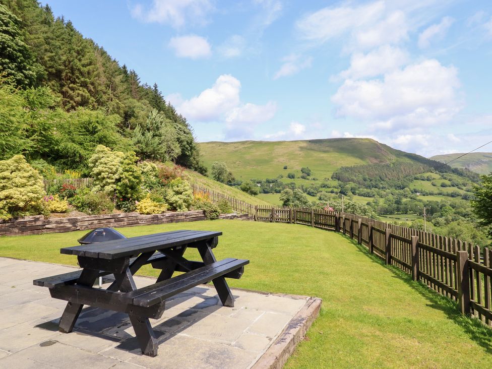 A garden with a picnic table and scenic mountains at Ysgubor Pwlliago in Pennant Valley near Llangynog