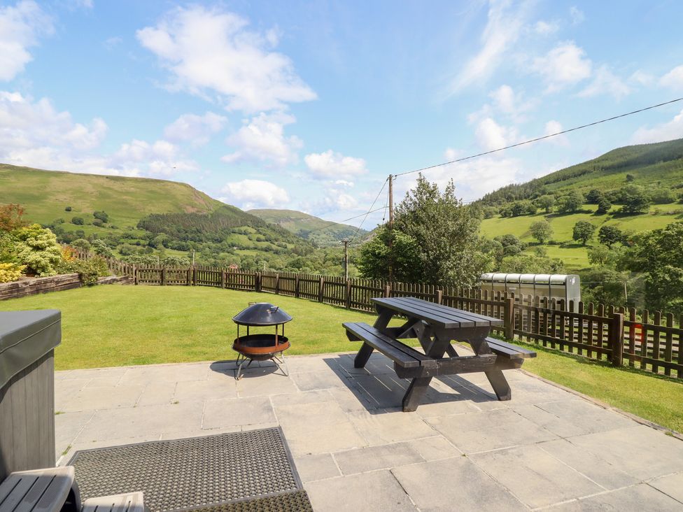 An outdoor patio with a table and fire pit at Ysgubor Pwlliago, Pennant Valley near Llangynog