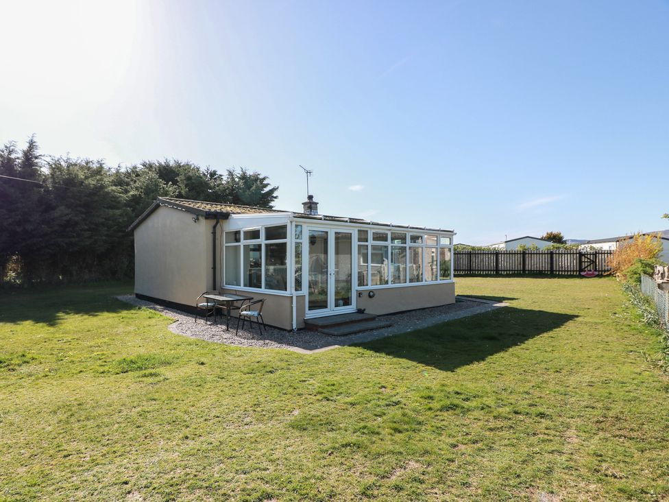 A conservatory with table and chairs in the garden at Kouloura Southerness