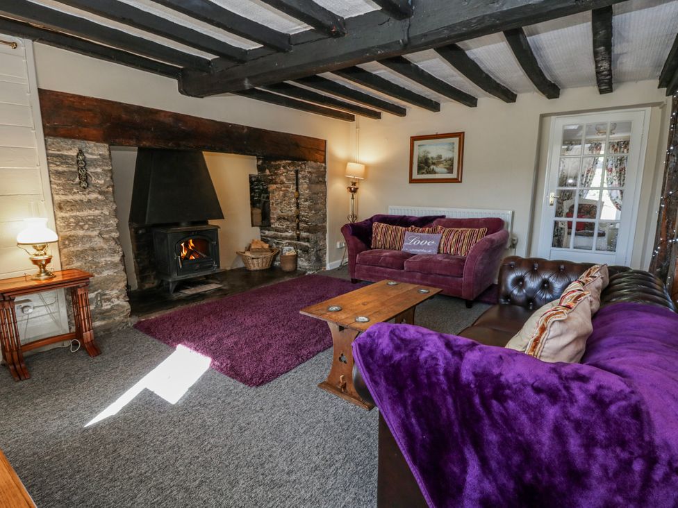 A living room with a fireplace and sofas at Penlone Cottage Rhayader