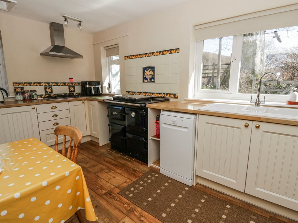 A kitchen with an oven, sink, and table at Penlone Cottage in Rhayader