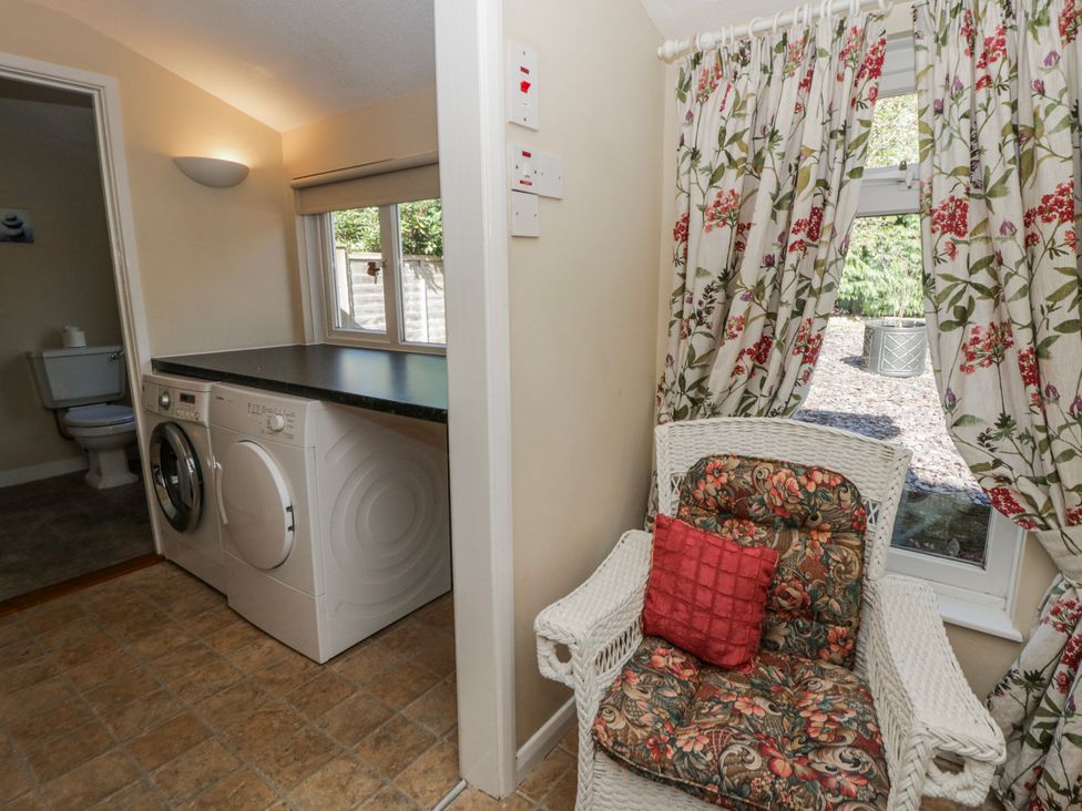A laundry room with a washing machine and a chair at Penlone Cottage in Rhayader