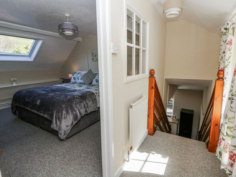 A bedroom with a bed and a staircase at Penlone Cottage in Rhayader