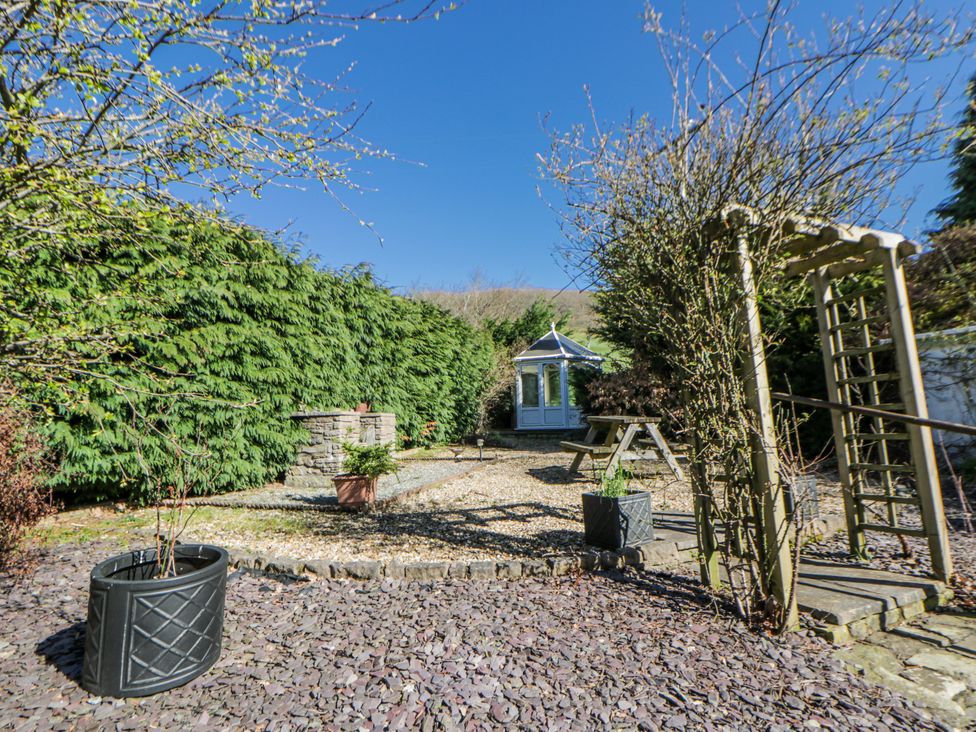 A garden with a shed and seating area at Penlone Cottage in Rhayader