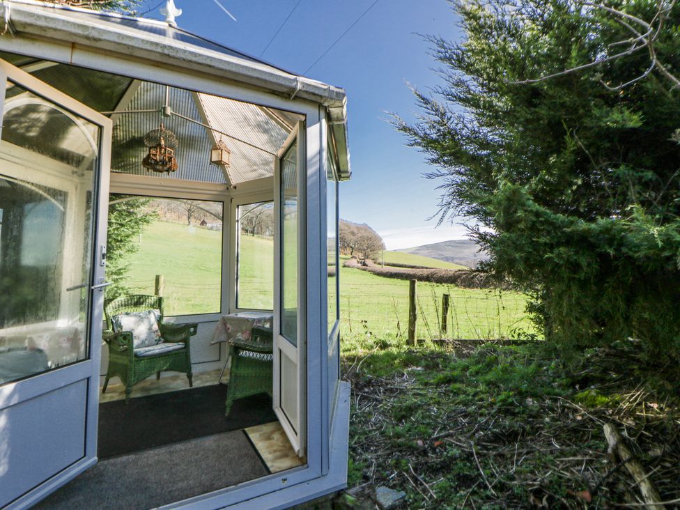 A conservatory with chairs and a view of the landscape at Penlone Cottage in Rhayader