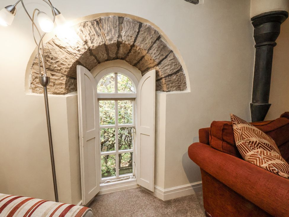 A living room with a stone arch window and a sofa at 1 The Old Methodist Chapel Rosedale Abbey