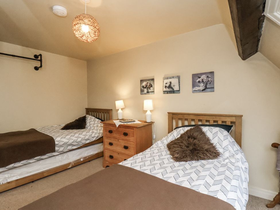 A bedroom with two beds, a lamp, and wall art at 1 The Old Methodist Chapel Rosedale Abbey