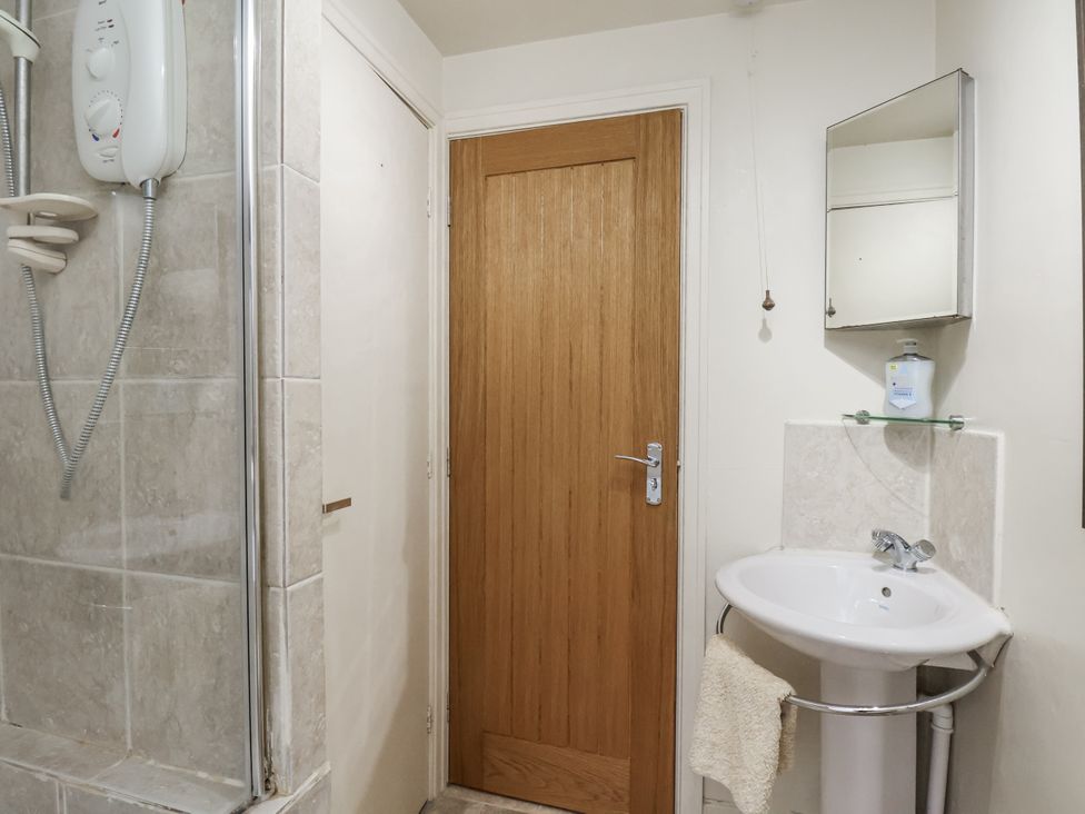 A bathroom with a shower, door, and sink at 1 The Old Methodist Chapel Rosedale Abbey