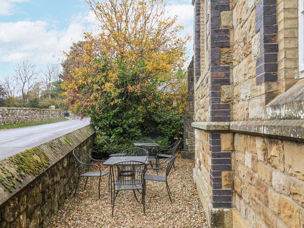 An outdoor area with a table and chairs beside a stone wall at 1 The Old Methodist Chapel Rosedale Abbey