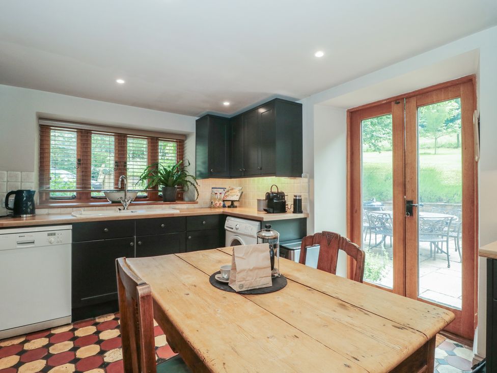 A kitchen with a wooden table and chairs at The Lodge Farm Barn in Deepdean near Ross-on-Wye